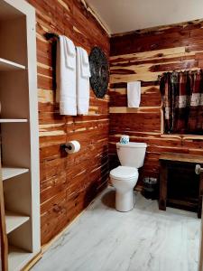 bagno con pareti in legno, servizi igienici e asciugamani. di Log Cabin Inn a Eureka Springs