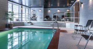 uma piscina num edifício com cadeiras e uma mesa em Wellness Hotel Šedý Vlk em Harrachov