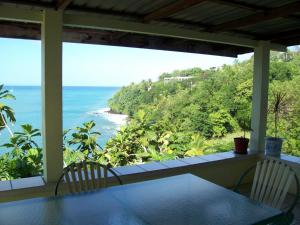 een veranda met een tafel en stoelen en uitzicht op de oceaan bij Casa del Vega a Little Peace of Heaven in Castries