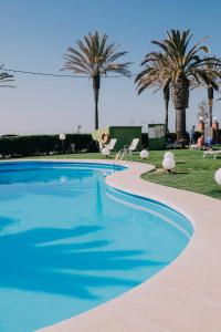 uma piscina com palmeiras ao fundo em Hotel Subur Maritim em Sitges