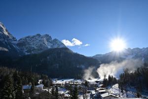 een met sneeuw bedekte bergketen met de zon in de lucht bij Das ALPSPITZ in Biberwier