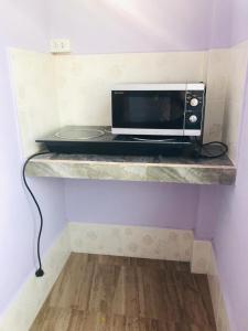 - un four micro-ondes installé sur une étagère dans une pièce dans l'établissement xaythone guest house, à Savannakhet