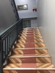 un escalier avec des balustrades en bois et en métal et un tapis dans l'établissement xaythone guest house, à Savannakhet