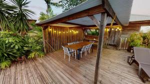 een houten terras met een tafel en stoelen erop bij Baobab Guadeloupe in Sainte-Anne