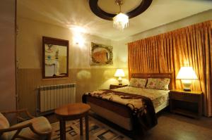 a bedroom with a bed and a chair and a chandelier at European Complex in Bhurban