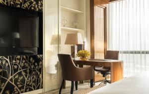 a bedroom with a desk and a bed with a laptop at Four Seasons Hotel Tianjin in Tianjin