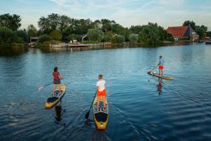 3 personnes sur des planches de paddle sur un lac dans l'établissement Pean-buiten Waterlodges, à Nes