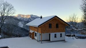 una casa nella neve con montagne sullo sfondo di Ferienhaus Oberschindlberg a Lunz am See