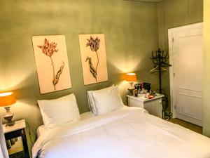 a bedroom with a white bed and two paintings on the wall at Hotel Beijers in Utrecht