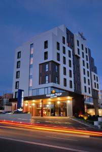 een hoog wit gebouw met een straat ervoor bij Golden Tulip Ana Dome Hotel in Cluj-Napoca