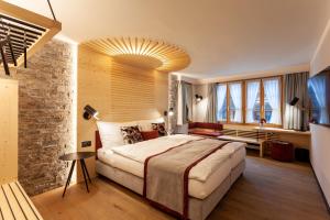 een grote slaapkamer met een groot bed en een stenen muur bij Sonne Andermatt Swiss Quality Hotel in Andermatt