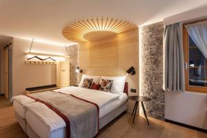 een slaapkamer met een groot bed en een groot plafond bij Sonne Andermatt Swiss Quality Hotel in Andermatt