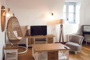 a living room with a tv and a chair and a table at Résidence de l'Arsenal Royal - Meublés de Tourisme in Rochefort