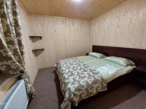 una camera con un letto in una stanza con pareti in legno di Приватна садиба Два сини та донька a Bukovel