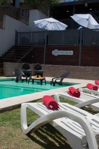 - une piscine avec 2 chaises longues et un parasol dans l'établissement Apart Porto del Sol by CPH, à Villa Carlos Paz