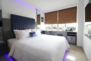 a bedroom with a large white bed and a kitchen at Moritz Biz Gandaria in Jakarta