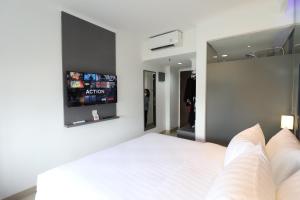 a bedroom with a white bed with a tv on the wall at Moritz Biz Gandaria in Jakarta