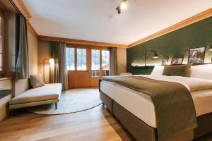 - une chambre avec un grand lit et une chaise dans l'établissement Hotel Fiescherblick, à Grindelwald