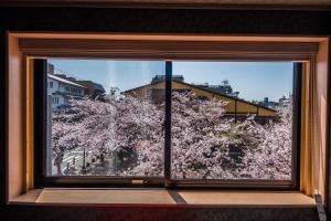 una finestra con vista su un albero con fiori rosa di Hotel Alza Kyoto a Kyoto