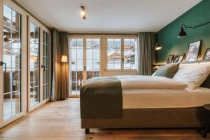 ein Schlafzimmer mit einem großen Bett und einer grünen Wand in der Unterkunft Hotel Fiescherblick in Grindelwald