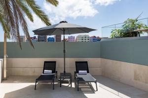 - deux chaises et une table avec un parasol sur le toit dans l'établissement Harbor Hotel & Casino Curacao, à Willemstad