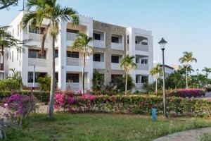 un grande edificio bianco con palme e fiori di The hayce residence a Kilifi