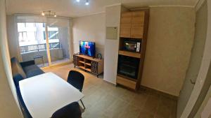 een woonkamer met een tafel en stoelen en een televisie bij Apart Hotel Bauerle & Apartamentos in Temuco