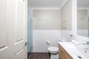 een witte badkamer met een toilet en een wastafel bij Aqua Lagoon - Great Family Beach Getaway in Nelson Bay