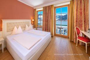 um quarto com uma cama, uma secretária e uma janela em Grand Hotel Zell am See em Zell am See