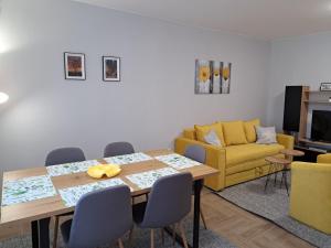 uma sala de jantar com uma mesa e um sofá amarelo em Apartments Manna Palic em Palić