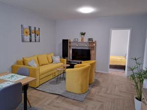 uma sala de estar com um sofá amarelo e cadeiras em Apartments Manna Palic em Palić