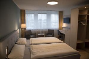 a hotel room with two beds and a desk at Hotel Am Friesenstrand in Butjadingen