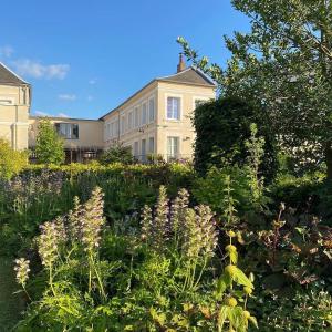 un jardin fleuri devant un bâtiment dans l'établissement Au Jardin des Deux Ponts, à Abbeville