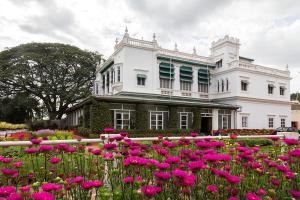 un campo di fiori rosa di fronte a un edificio bianco di The Green Hotel a Mysore