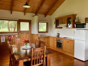 Il comprend une cuisine équipée d'une table et d'un réfrigérateur blanc. dans l'établissement Daysy Hill Country Cottages, à Port Campbell