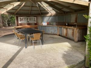 d'une terrasse avec une table, des chaises et un bar. dans l'établissement Daysy Hill Country Cottages, à Port Campbell