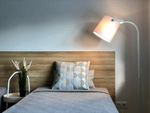 - une chambre avec un lit doté d'une lampe et d'un oreiller dans l'établissement COMFY Patogūs namai, à Kaunas