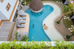 - une vue sur la piscine avec 2 personnes et des parasols dans l'établissement Roomates Surf Camp Canggu by Ini Vie Hospitality, à Canggu