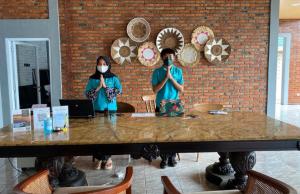 deux personnes portant un masque facial debout à une table dans l'établissement Alinson Sunset Hill, à Bogor