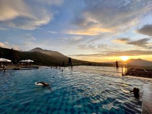 une personne se baignant dans une piscine avec le coucher du soleil en arrière-plan dans l'établissement Alinson Sunset Hill, à Bogor