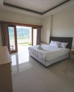 a bedroom with a large bed and a large window at GREEN RINJANI in Bayan