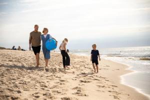 una familia caminando por la playa con una pelota azul en Lalandia Søndervig, en Søndervig