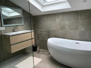 a bathroom with a white tub and a sink at Charmant chalet, spacieux, proche du lac, vue sur la montagne in Gérardmer