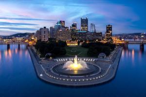 um horizonte da cidade à noite com uma fonte na água em Hyatt Place Pittsburgh North Shore em Pittsburgh