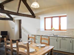 - une salle à manger avec une table et des chaises en bois dans l'établissement The Barn, à Talsarnau