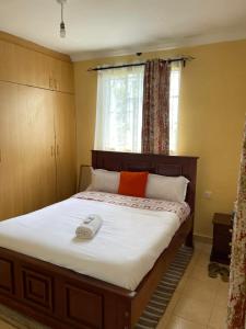 ein Schlafzimmer mit einem Bett und einem Telefon darauf in der Unterkunft Zoe Homes 1br and 2br Cottage own compound -Kericho town near Green Square mall in Kericho