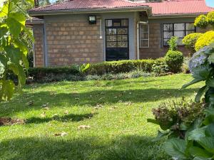 ein Haus mit einem Rasenhof mit einem Haus in der Unterkunft Zoe Homes 1br and 2br Cottage own compound -Kericho town near Green Square mall in Kericho