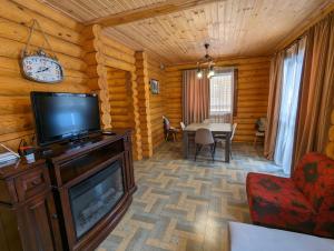 - un salon avec une télévision et une table à manger dans l'établissement LOG HOUSE, à Bakuriani