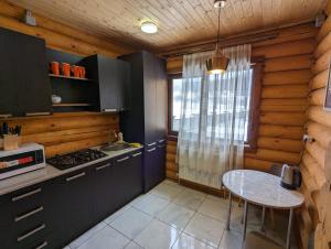 une cuisine avec une table et une cuisinière ainsi qu'une fenêtre dans l'établissement LOG HOUSE, à Bakuriani