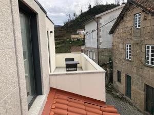 un balcón con una silla negra en un edificio en Casa da Forja, en Aldeia das Dez